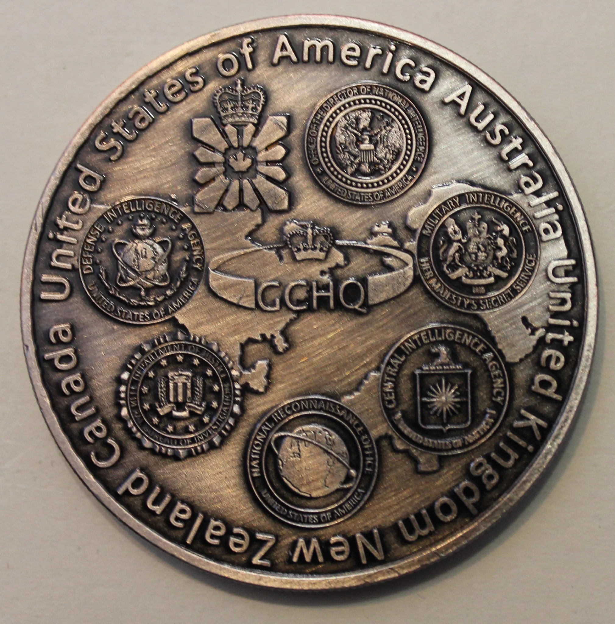 Five Eyes Guts Agentic Rollouts: a close-up of a silver coin featuring emblems and text representing the intelligence alliance of Five Eyes countries.