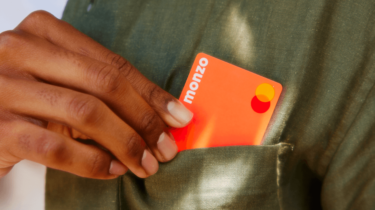 A person is placing a Monzo card into their jacket pocket.